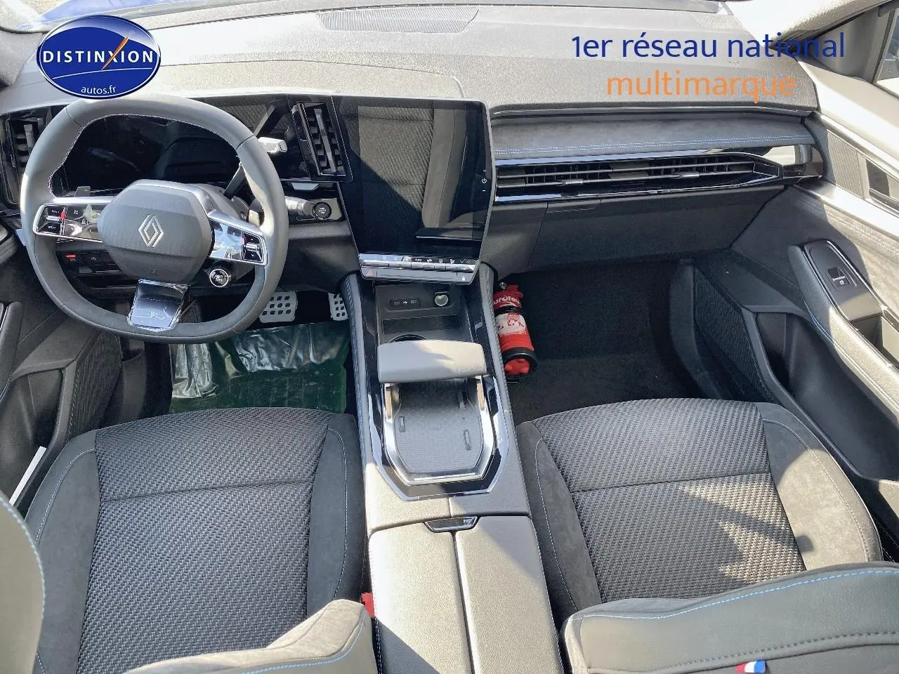 Intérieur avant du Renault Austral 2025, sièges noirs avec surpiqûres bleues et console centrale moderne avec écran tactile.