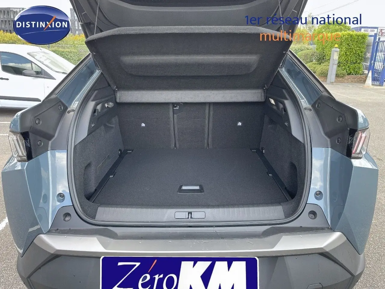Coffre ouvert vu de l'arrière d'un Peugeot 3008 Hybrid bleu Ingaro Metal, montrant l'espace de chargement vide.