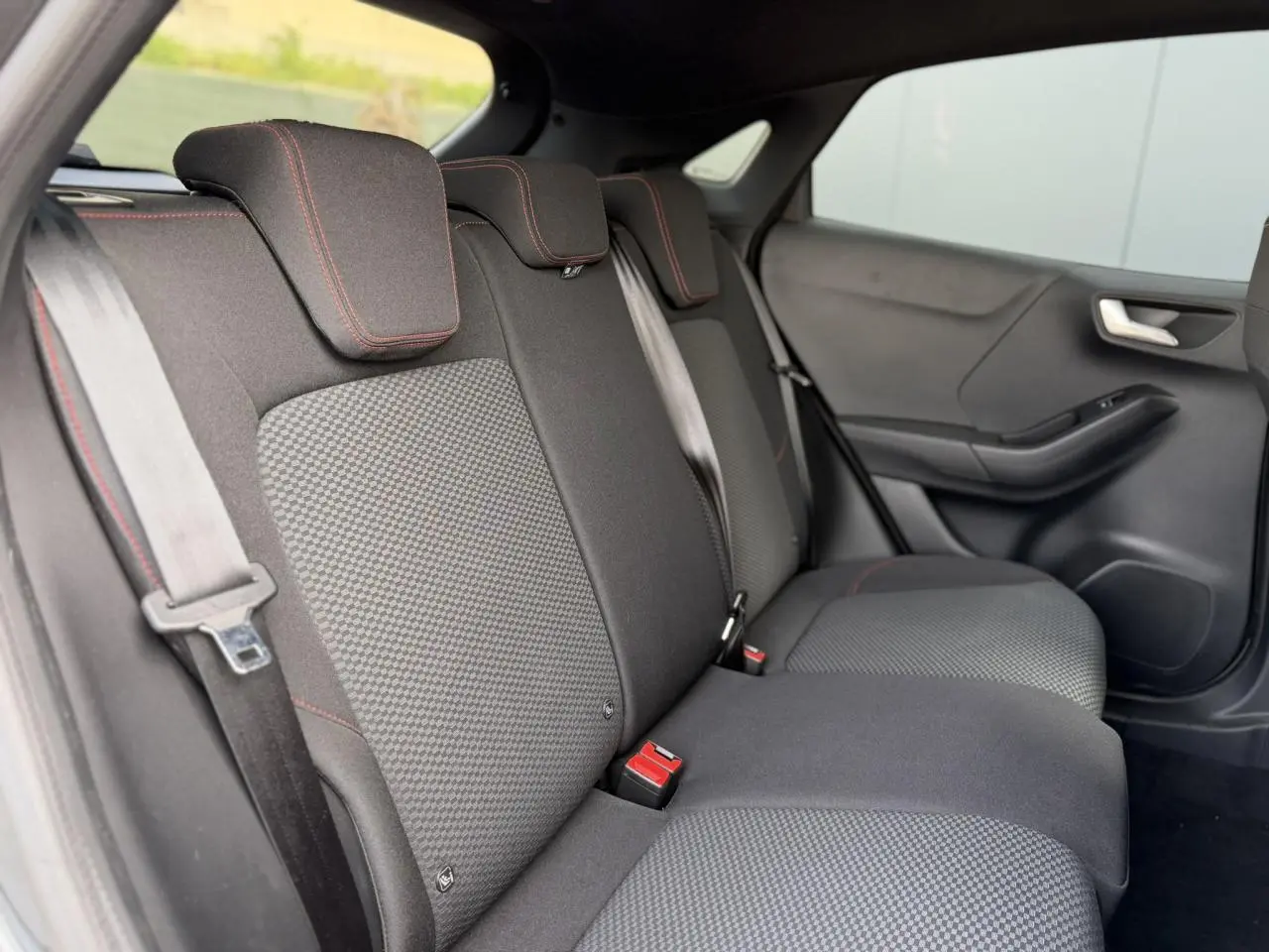 Vue intérieure côté droit des sièges arrière noirs avec surpiqûres rouges du Ford Puma Ecoboost 155 BVA ST Line 2024.