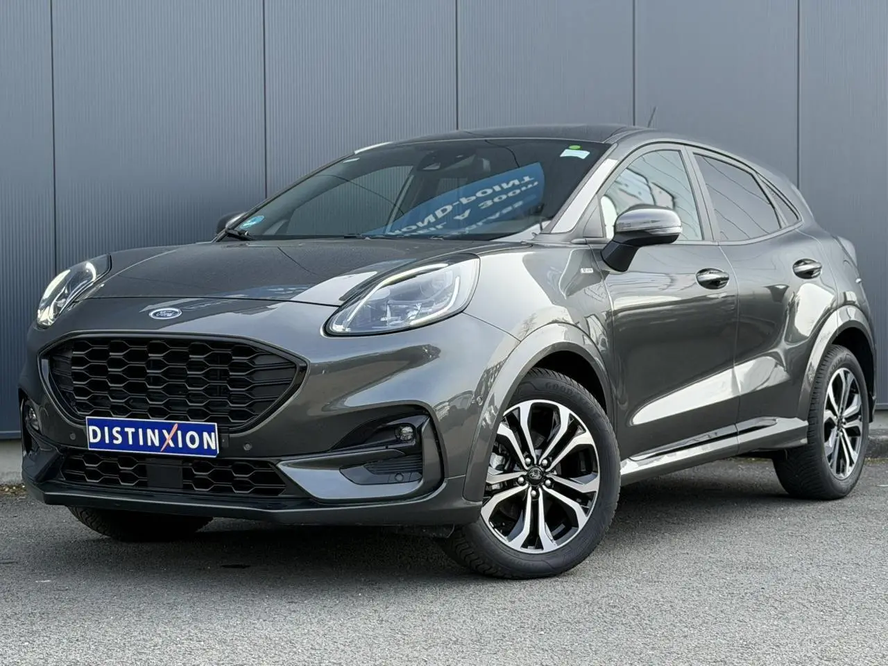 Ford Puma Ecoboost gris magnétique en 3/4 avant droit, avec calandre noire et jantes alliage diamantées 17 pouces.