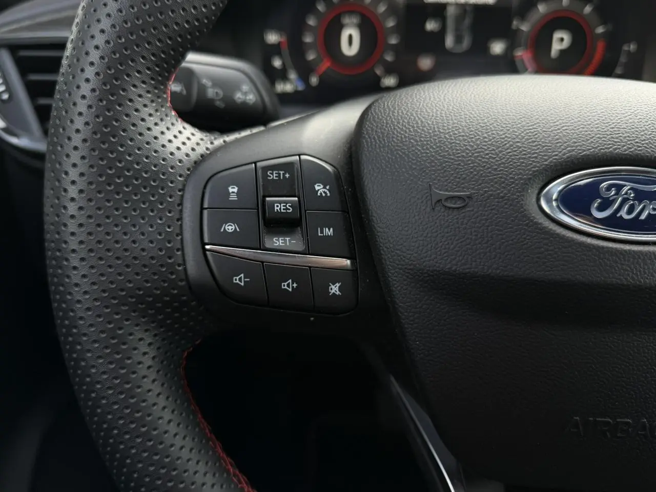 Gros plan sur le volant perforé noir ST-Line du Ford Puma 2024 avec commandes intégrées et logo Ford central.