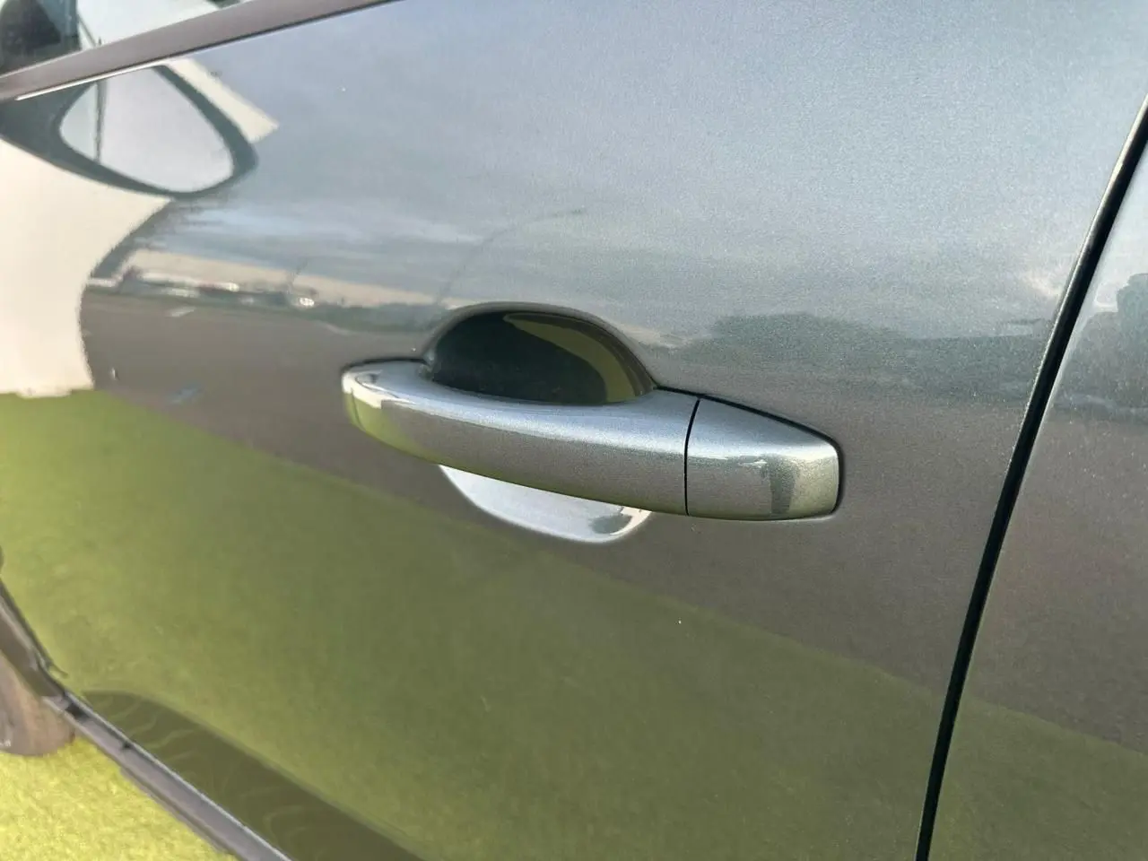 Poignée de porte avant droite de Dacia Sandero III Stepway 2025 en Vert Cèdre avec reflet métallique.