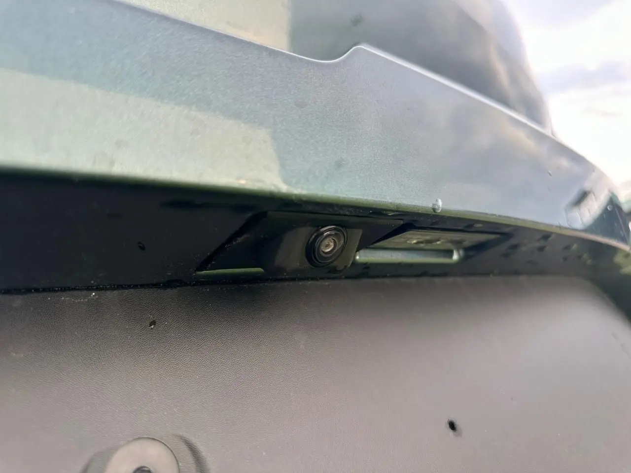 Gros plan sur la caméra de recul sous le pare-chocs arrière du Dacia Sandero III Stepway Vert Cèdre.