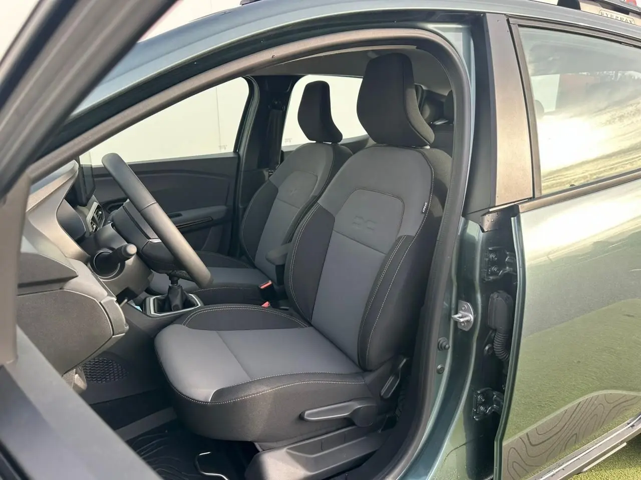 Vue intérieure côté conducteur de la Dacia Sandero III Stepway 2025 vert cèdre, montrant les sièges avant et le volant.
