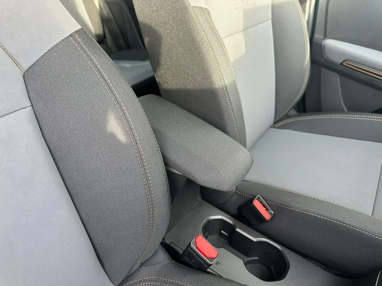 Gros plan sur l'accoudoir central et les sièges avant gris avec surpiqûres contrastantes de la Dacia Sandero III Stepway.