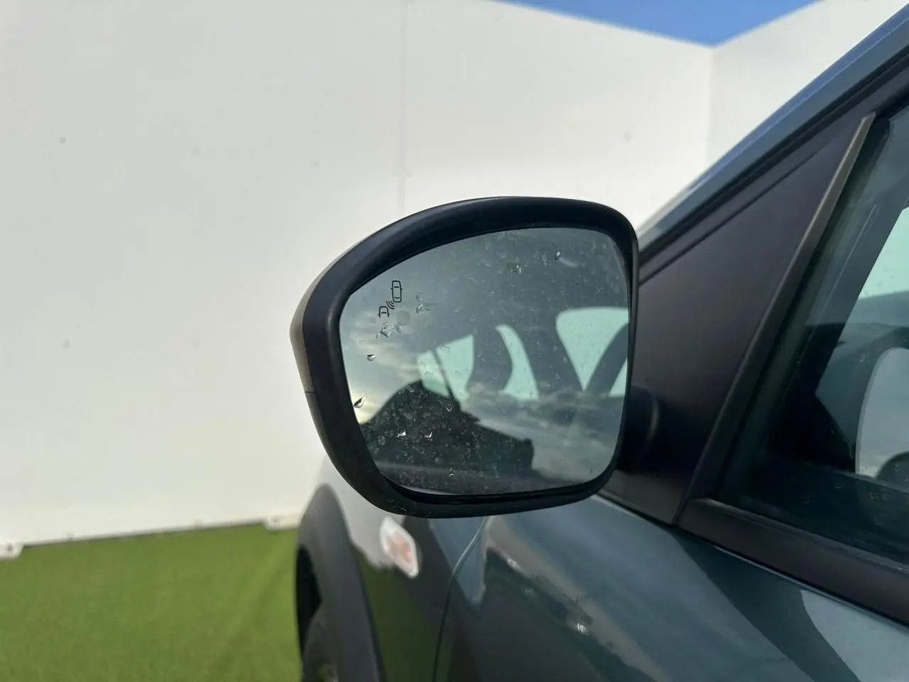 Rétroviseur droit de la Dacia Sandero III Stepway vert cèdre, avec capteur d’angle mort visible sur le miroir.