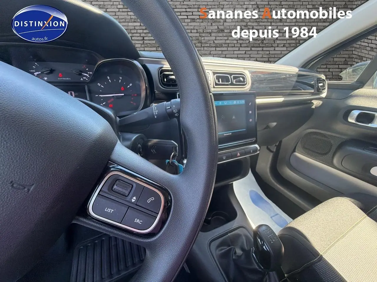 Intérieur de la Citroën C3 2022 gris foncé, vue côté conducteur sur volant, tableau de bord et levier de vitesses manuel.