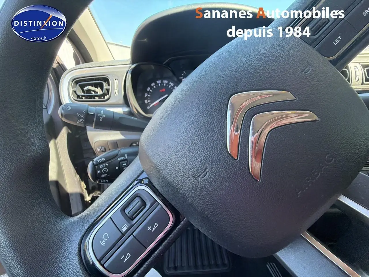 Gros plan sur le volant noir de la Citroën C3 2022 avec commandes audio intégrées et logo chromé au centre.