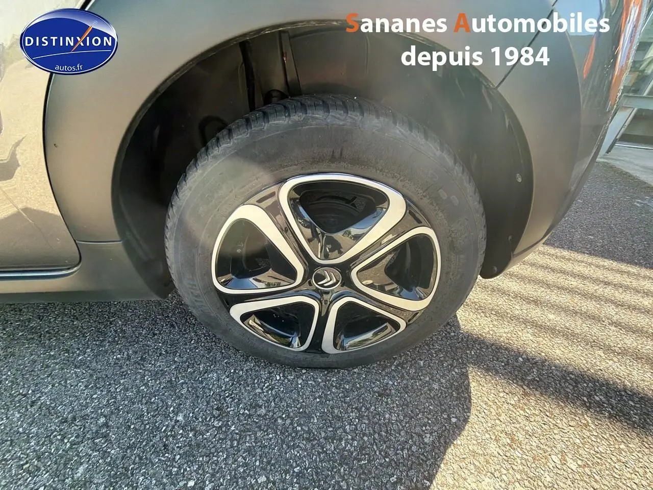 Gros plan sur la roue avant droite d'une Citroën C3 gris foncé avec jante noire et argentée distinctive.