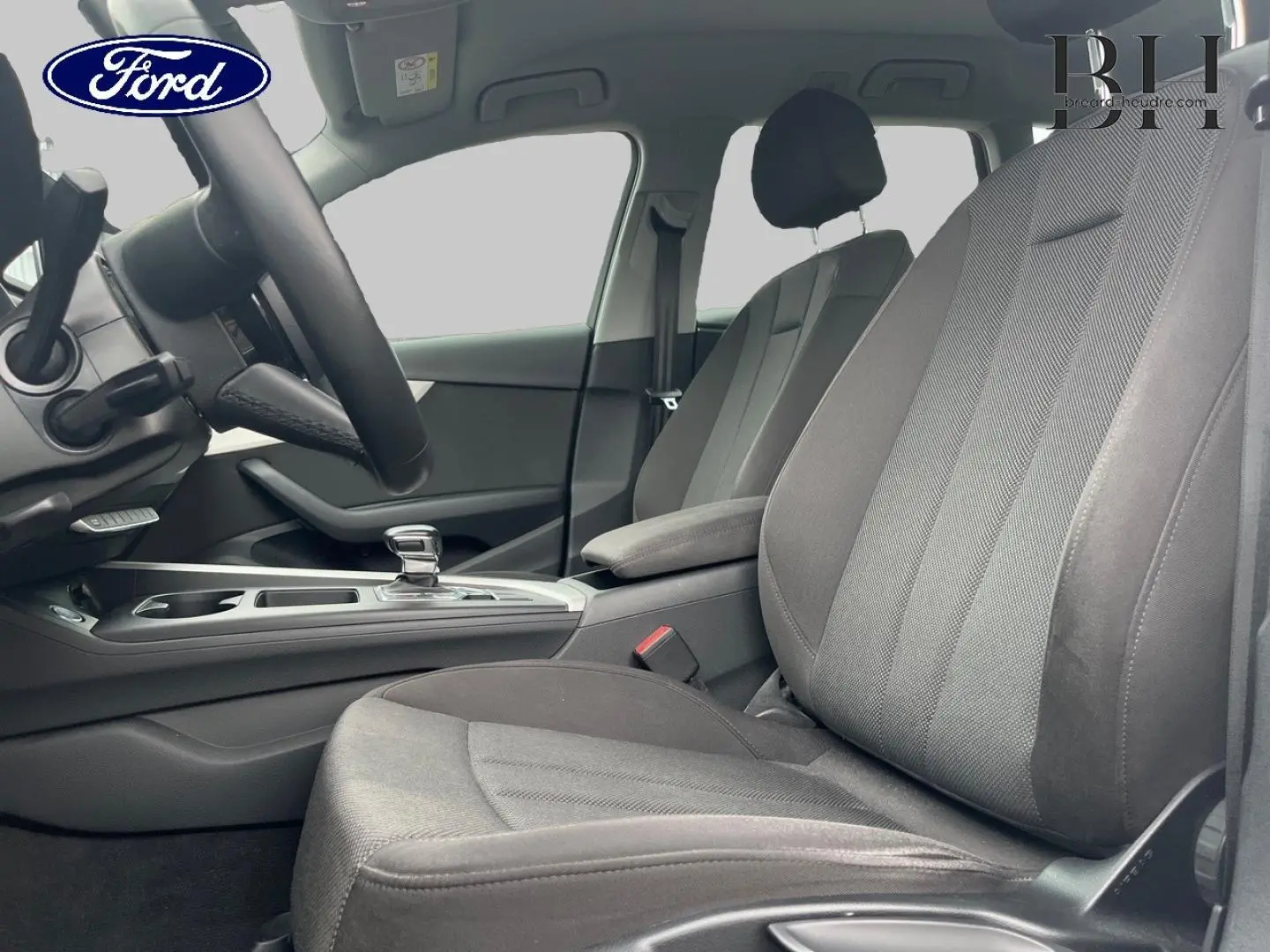 Vue intérieure côté conducteur de l'Audi A4 Avant 30 TDI 2021, sièges tissu gris et console centrale avec levier automatique.
