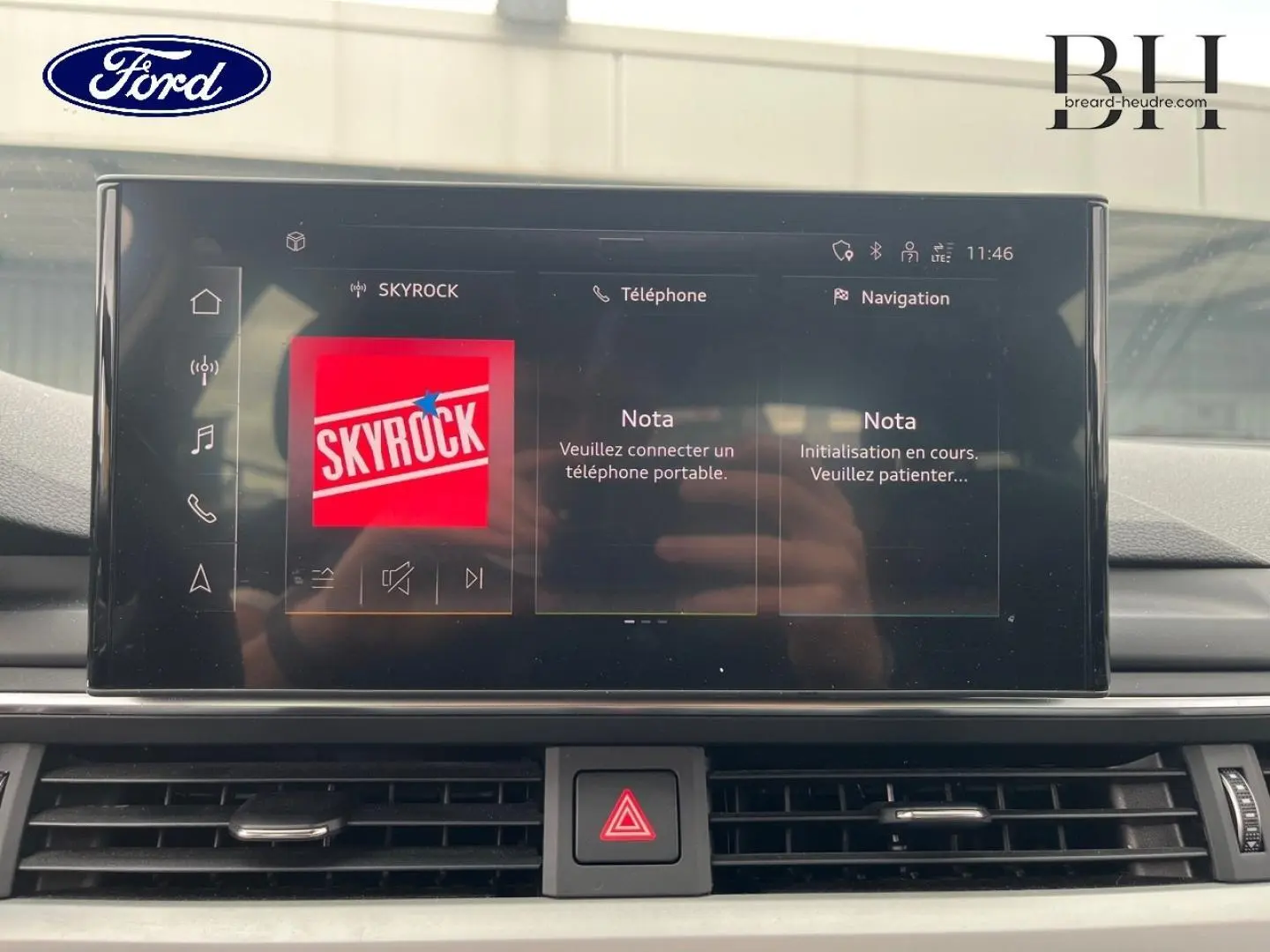 Vue rapprochée de l'écran tactile central de l'Audi A4 Avant blanc glacier, affichant l'interface multimédia Skyrock.