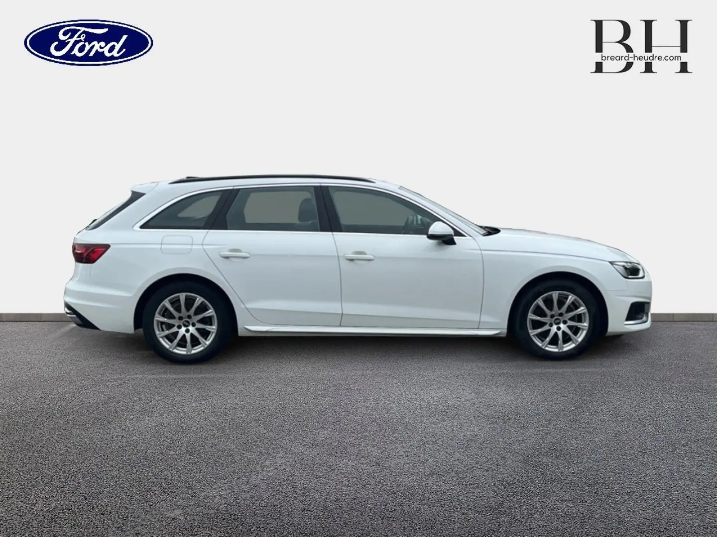 Profil droit d'une Audi A4 Avant blanc glacier métallisé, jantes alliage et barres de toit visibles.
