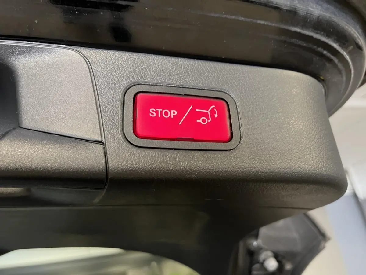 Bouton rouge d'arrêt électrique du hayon sur le coffre noir d'une Mercedes Classe B 180 d 2019 vue en gros plan.