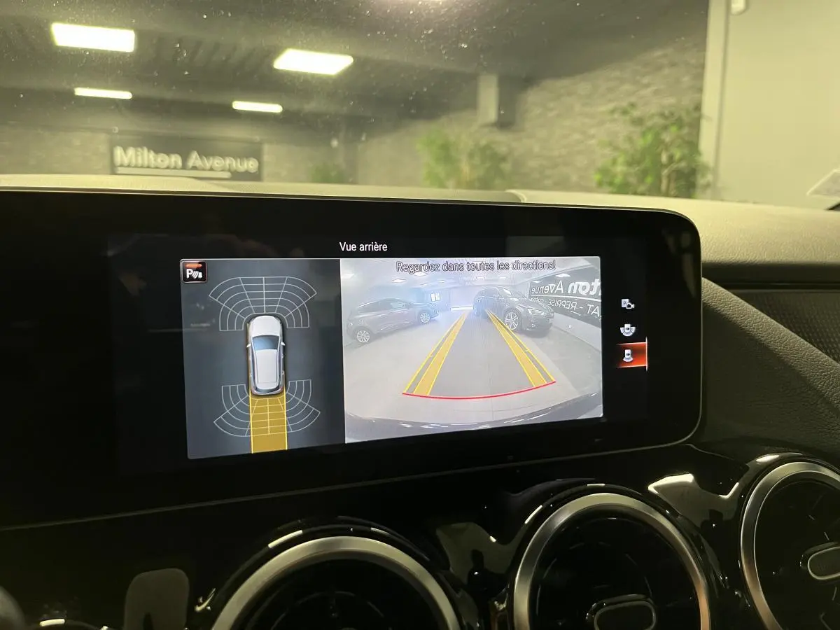Écran central tactile montrant la caméra de recul et l’aide au stationnement d’une Mercedes Classe B noire de 2019.