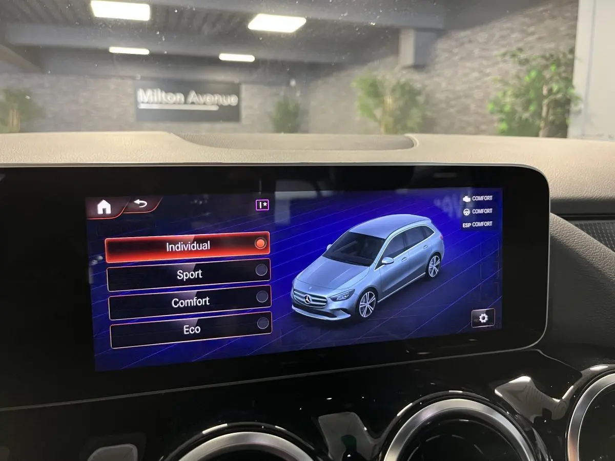 Écran tactile central affichant les modes de conduite avec une illustration 3D argentée de la Mercedes Classe B.