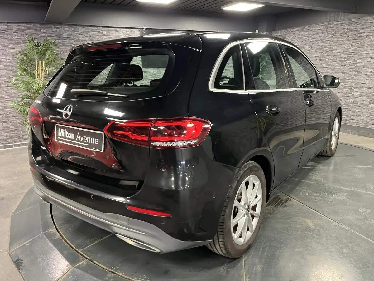 Vue 3/4 arrière droite d'une Mercedes Classe B noire avec feux LED et jantes alliage 17 pouces dans un showroom.