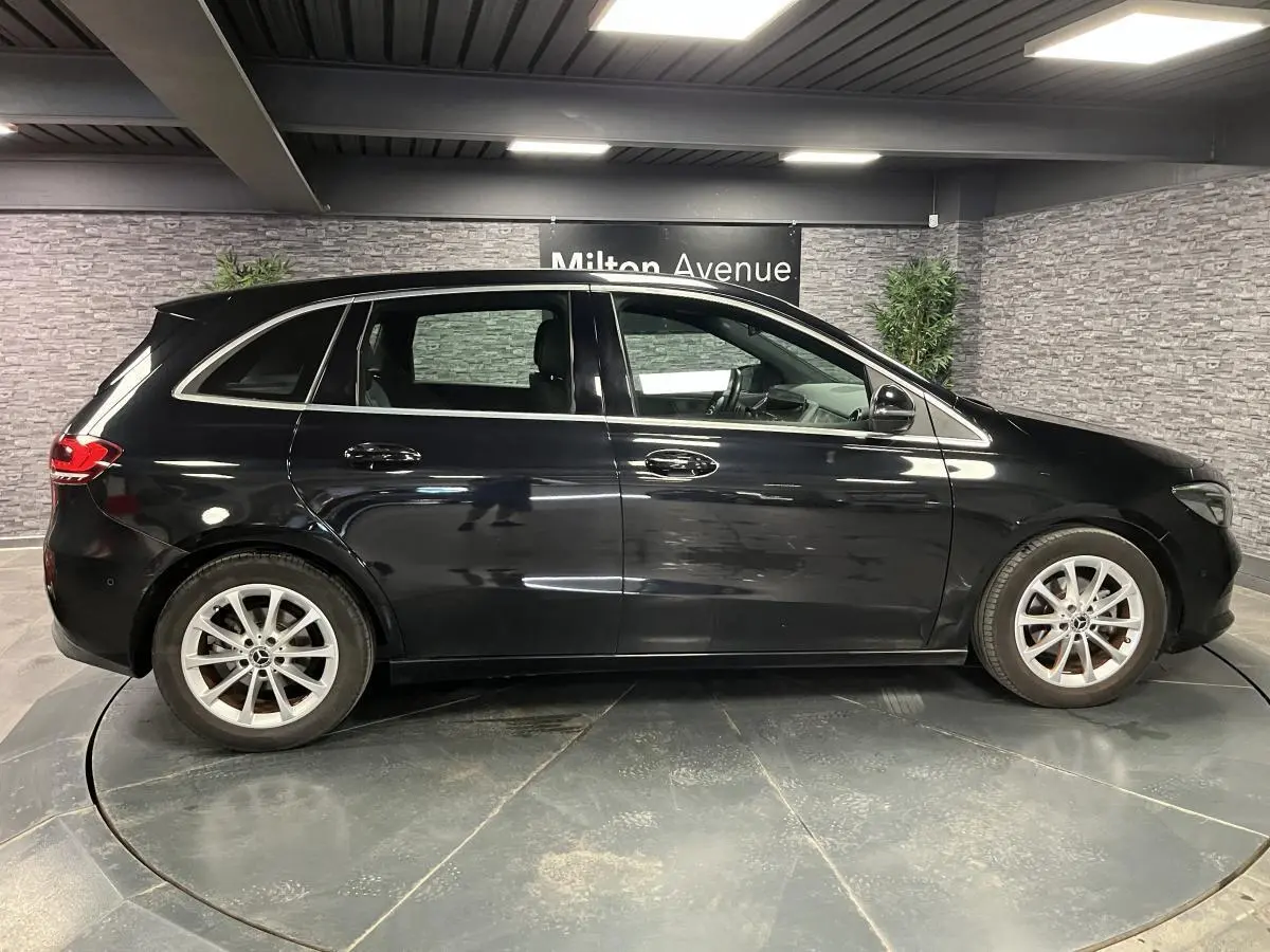 Mercedes Classe B 180 d noire vue de profil côté gauche, avec jantes alliage argent et poignées chromées.