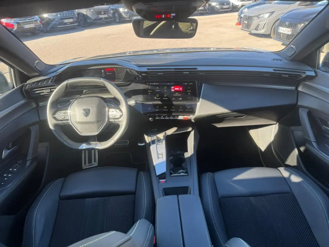 Vue intérieure avant de la Peugeot 408 Hybrid gris, avec volant cuir compact, cockpit numérique et console centrale moderne.