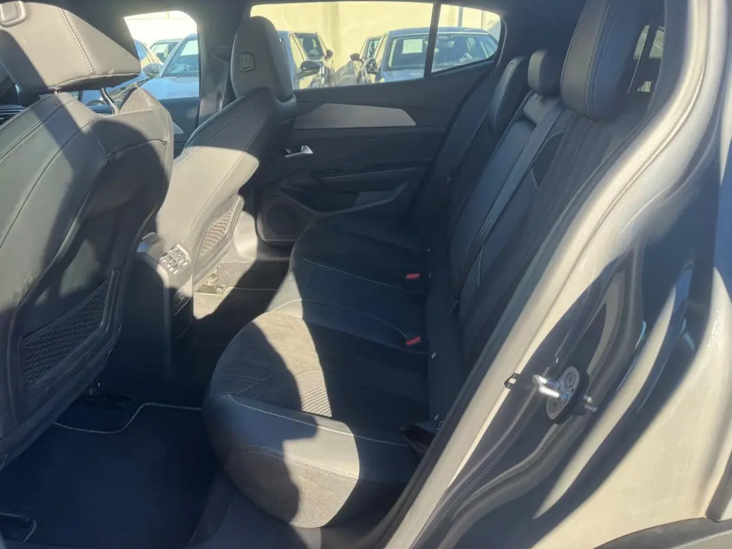 Vue côté droit de l'habitacle arrière gris du Peugeot 408 Hybrid 136 e-DCS6 GT avec sièges en tissu et cuir.