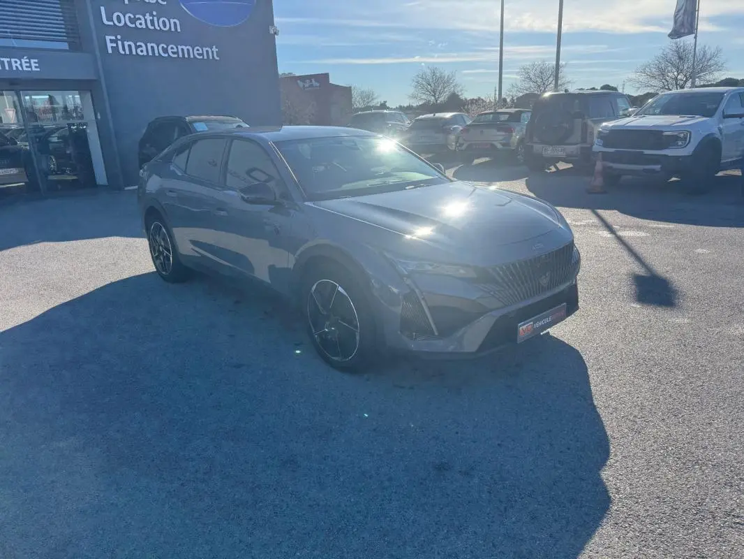 Peugeot 408 Hybrid gris en 3/4 avant droit, avec jantes alliage noires et calandre distinctive GT.