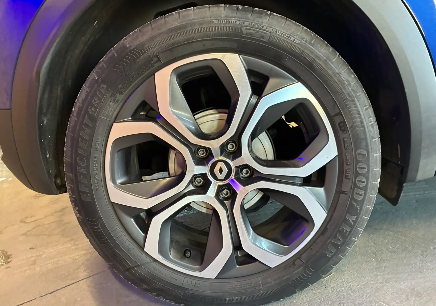 Gros plan sur la roue avant gauche d’un Renault Captur bleu 2021, mettant en valeur le pneu Goodyear et l’arche de roue noire.