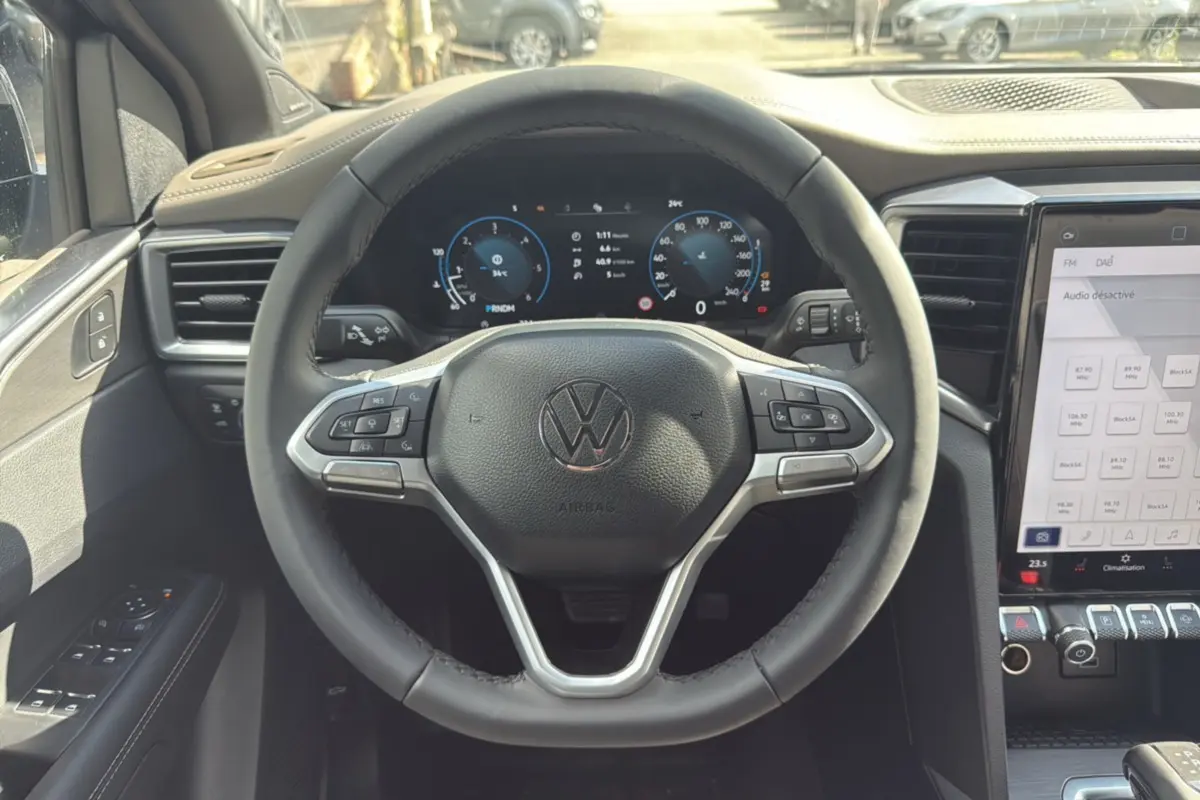 Vue intérieure centrée sur le volant cuir multifonctions et le tableau de bord digital du Volkswagen Amarok gris foncé.