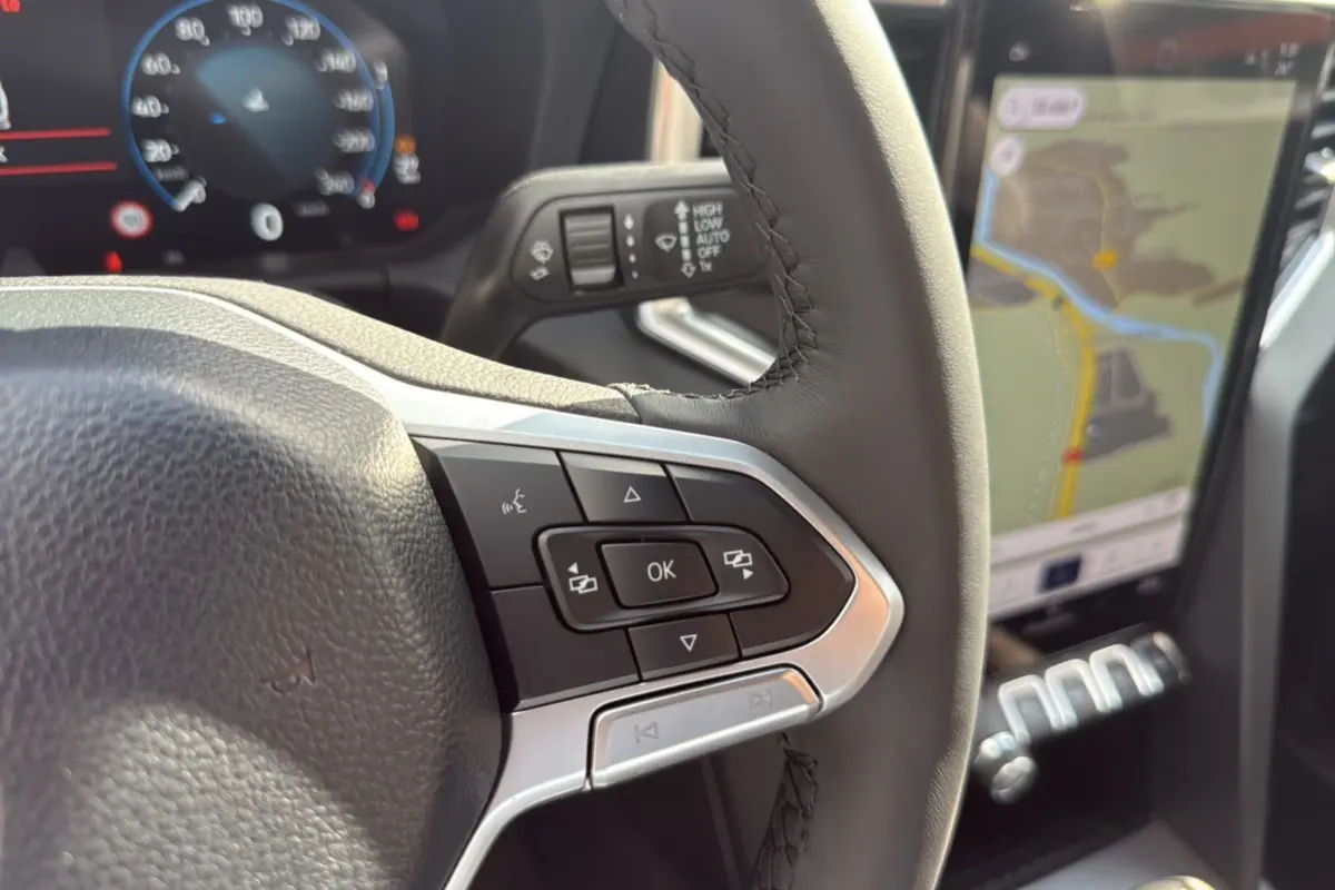 Gros plan sur le volant cuir multifonctions et l’écran tactile GPS du Volkswagen Amarok Simple Cabine gris foncé.