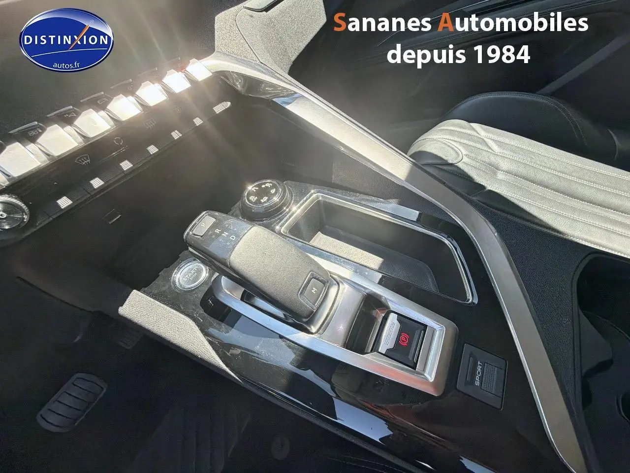 Gros plan sur la console centrale noire avec levier de vitesse et bouton start du Peugeot 3008 blanc, intérieur cuir clair.