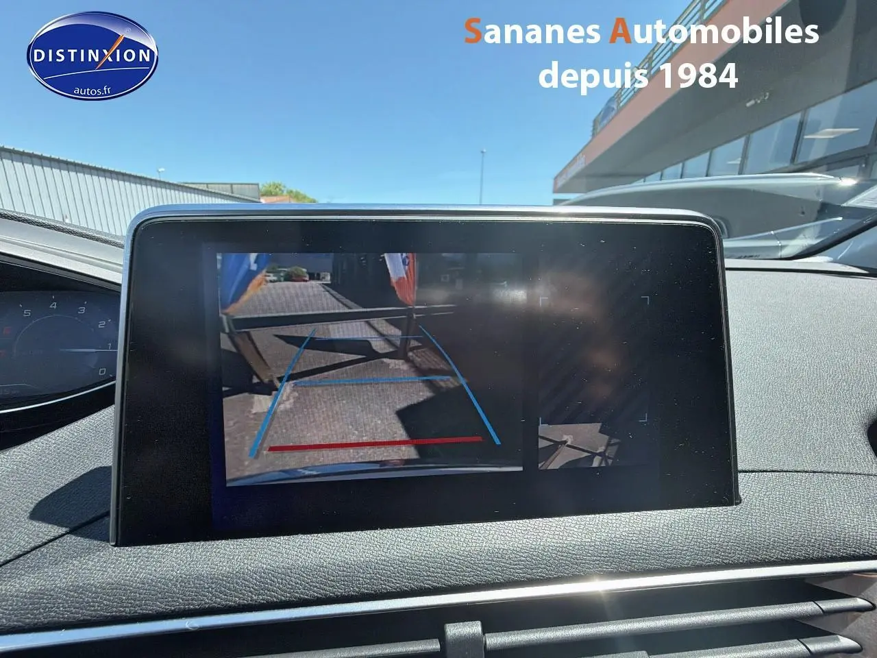 Écran tactile intérieur montrant la caméra de recul du Peugeot 3008 blanc, avec lignes de guidage bleues et rouges.