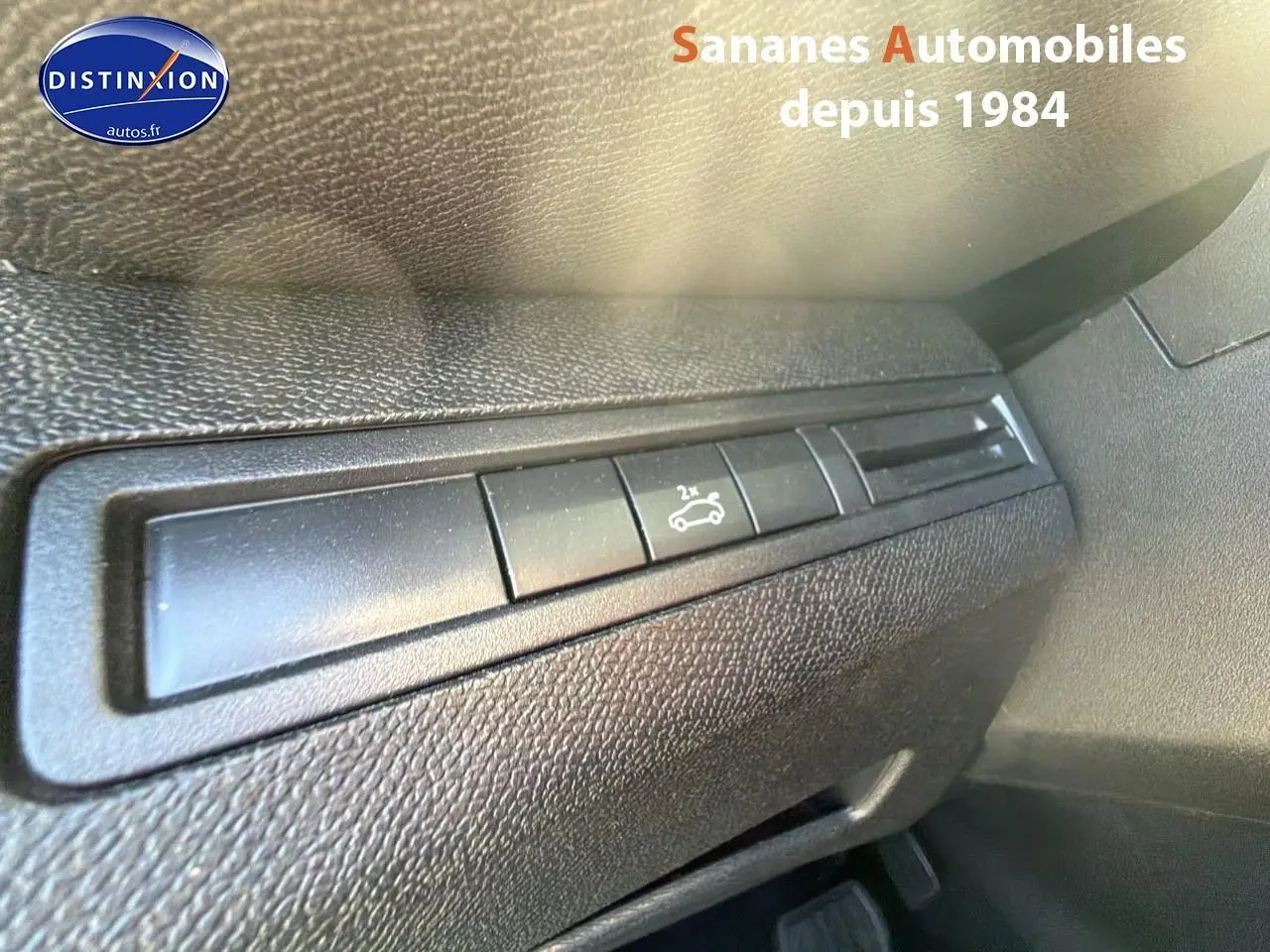 Détail du bouton d'ouverture du hayon sur le tableau de bord intérieur d'un Peugeot 3008 blanc.