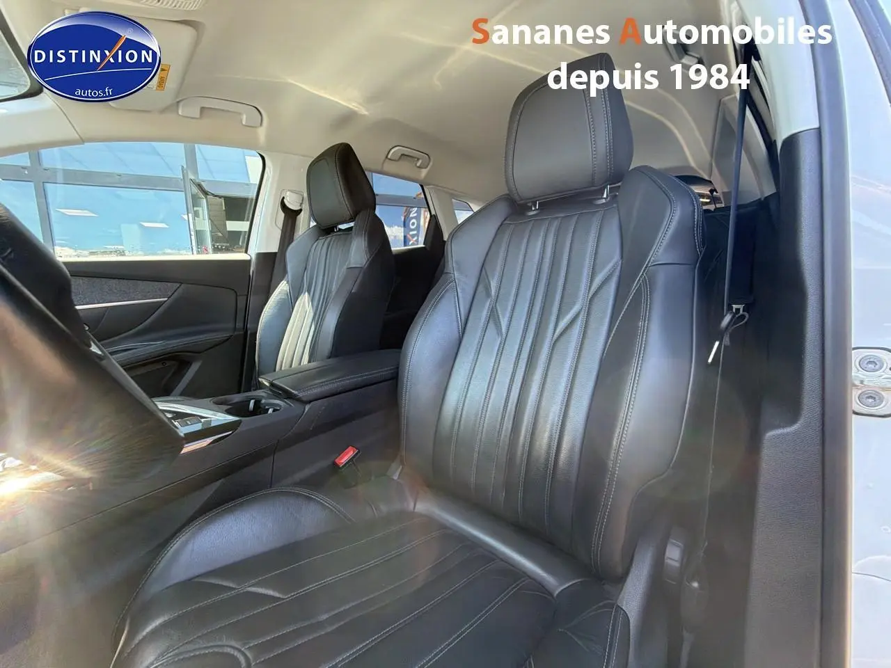 Vue intérieure côté avant droit du Peugeot 3008 blanc, mettant en valeur les sièges en cuir noir et la console centrale.