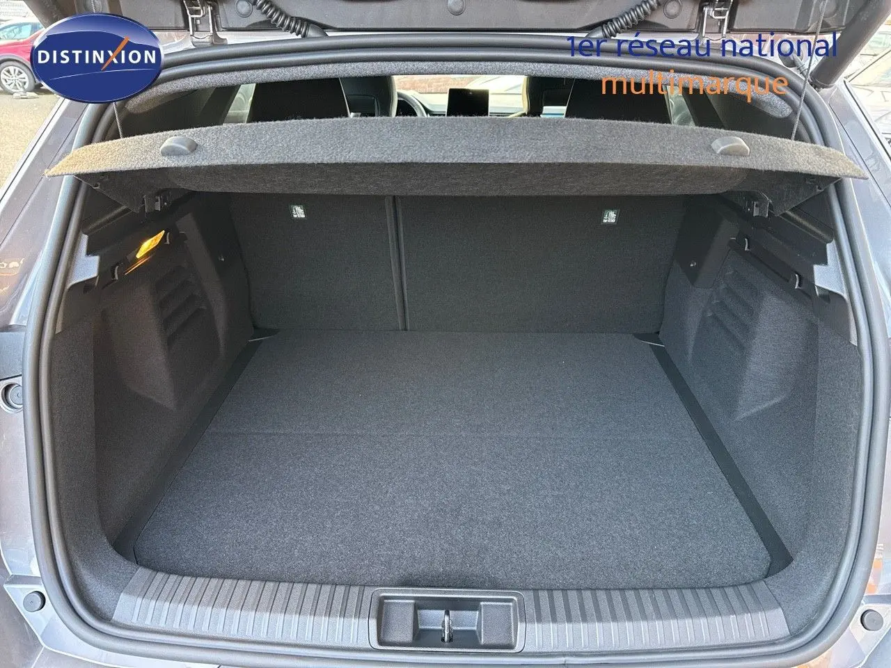 Coffre ouvert d'une Renault Symbioz gris Cassiope, vue arrière montrant l'espace de chargement et la tablette cache-bagages.