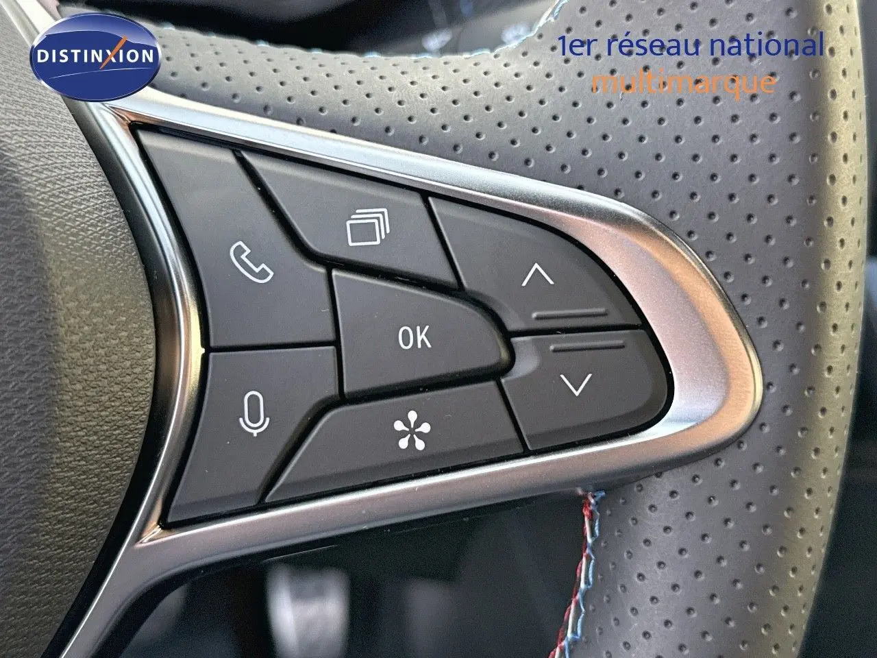Gros plan sur les commandes multifonctions du volant perforé du Renault Symbioz gris Cassiope, version E-Tech 145 Esprit Alpine.