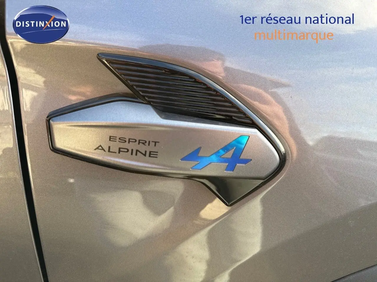 Détail de l'emblème Esprit Alpine bleu sur la portière côté gauche d'une Renault Symbioz gris Cassiope 2024.