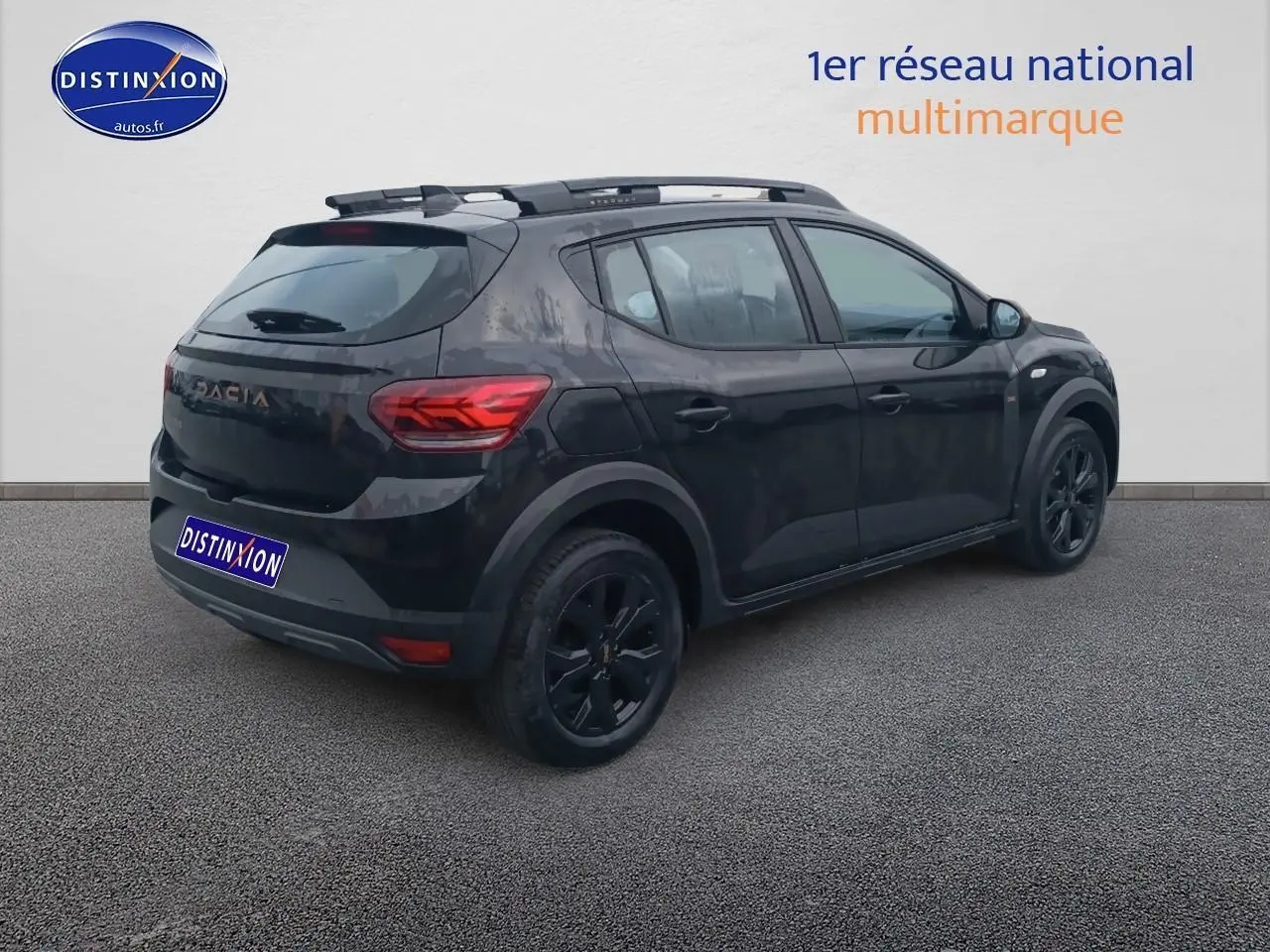 Vue 3/4 arrière droite d'une Dacia Sandero Stepway noire avec barres de toit et jantes alu noires.