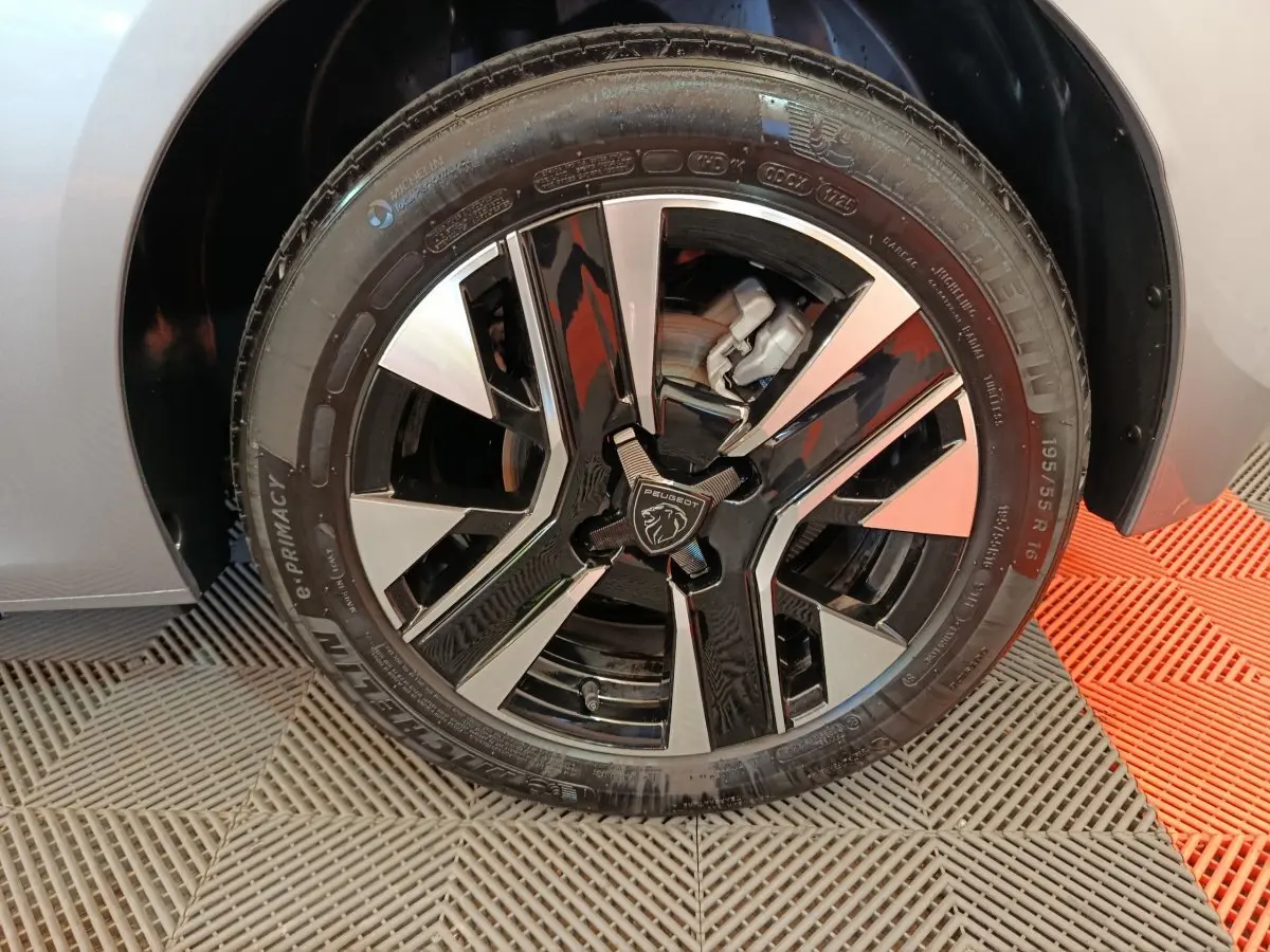 Gros plan sur la roue avant droite grise de la Peugeot 208 PureTech 100 avec jante alliage bicolore noire et argent.