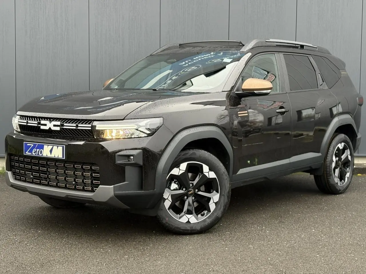 Vue 3/4 avant droit du Dacia Bigster noir nacré avec rétroviseurs cuivrés et jantes alliage 18 pouces.