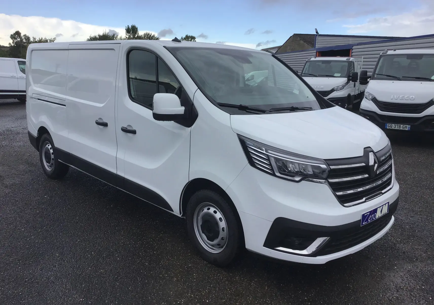 Renault Trafic Fourgon blanc en vue 3/4 avant droit, avec calandre noire et phares LED distinctifs.