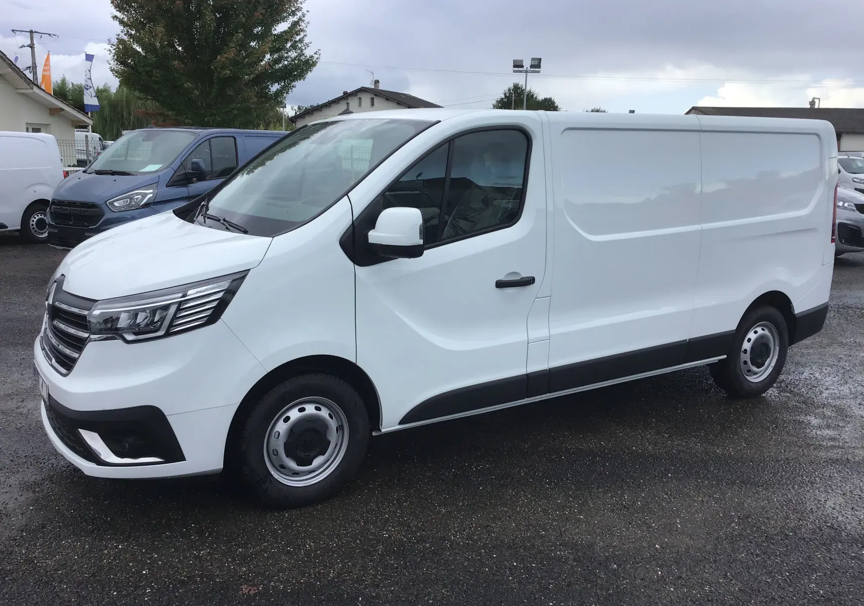 Renault Trafic Fourgon blanc vu de profil côté gauche, avec calandre noire et jantes acier simples.