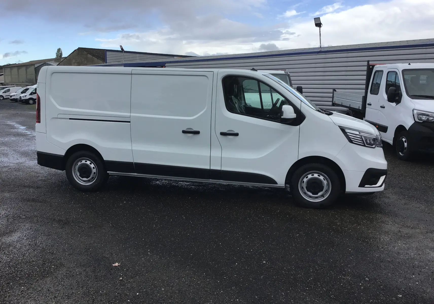 Renault Trafic Fourgon blanc vu de profil côté droit, avec portes coulissantes et jantes acier simples.