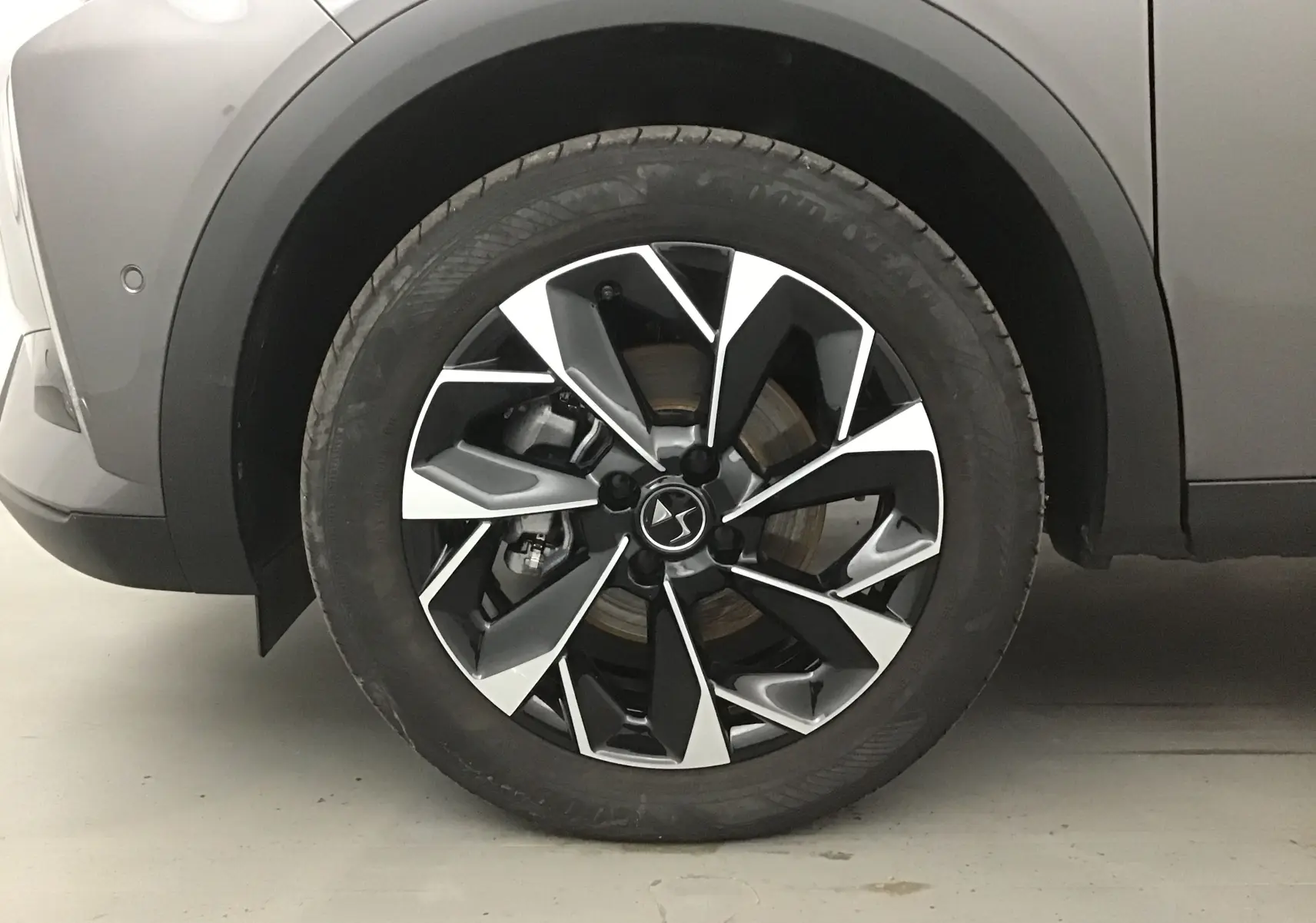 Gros plan sur la roue avant gauche du DS3 Crossback gris platinium, mettant en valeur la jante noire et argentée au design moderne.