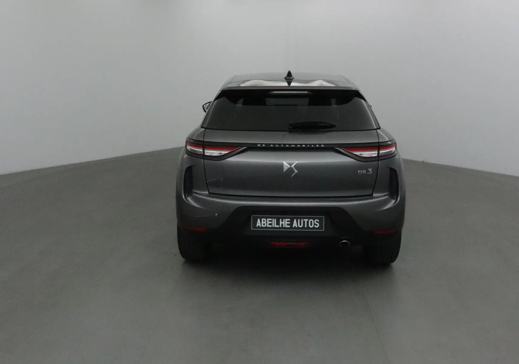 Vue arrière d'un DS3 Crossback gris platinium 2024 avec feux LED et logo DS visible sur fond neutre.