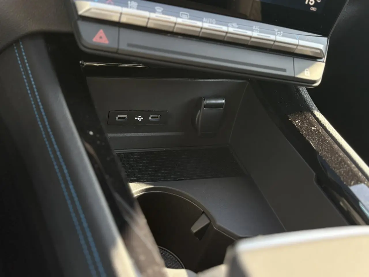 Gros plan sur la console centrale noire du Renault Austral E-Tech avec ports USB-C et rangement sous le tableau de bord.