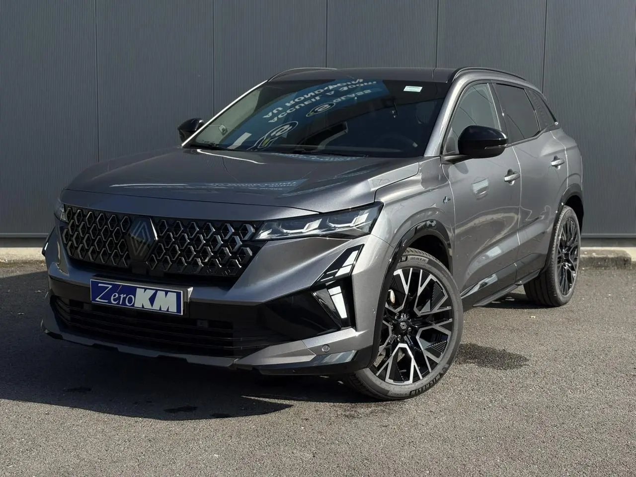 Renault Austral gris schiste en 3/4 avant droit, avec jantes alliage noires et calandre hexagonale distinctive.