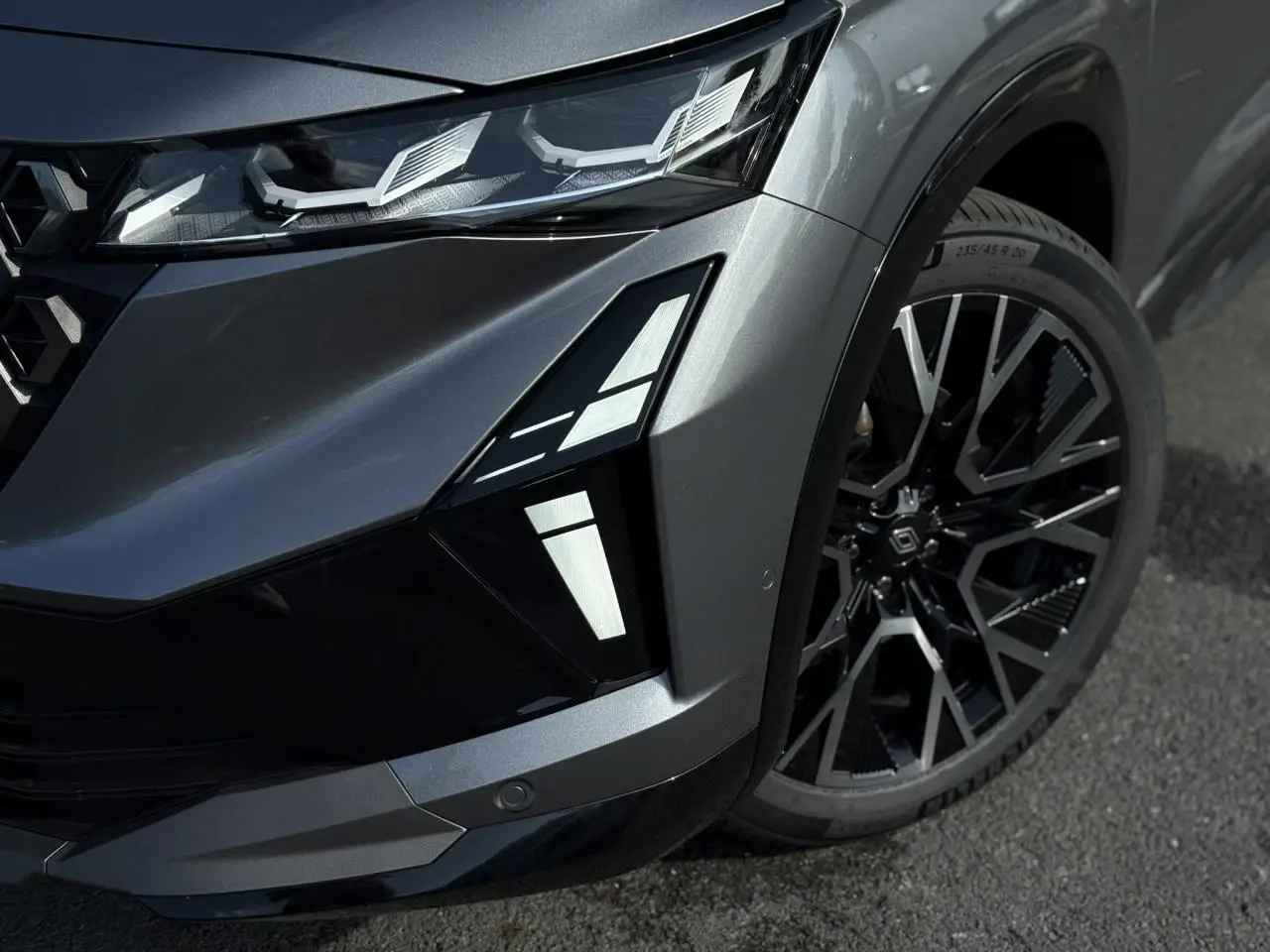 Gros plan sur l'avant droit gris schiste du Renault Austral E-Tech, mettant en valeur les feux LED et la jante alliage noire diamantée.