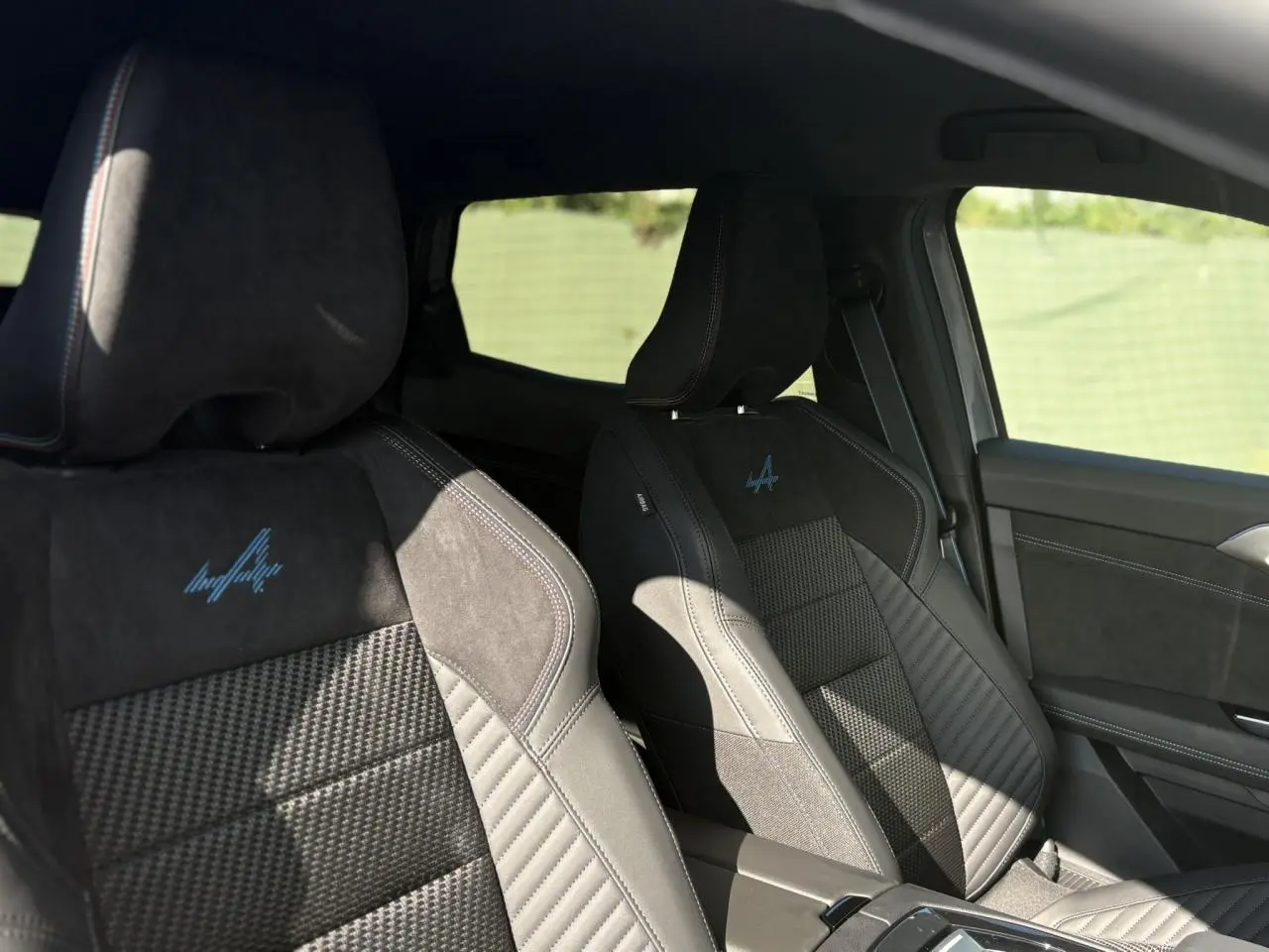 Sièges avant noirs en Alcantara avec logo Alpine brodé, vue intérieure côté conducteur du Renault Austral 2025.