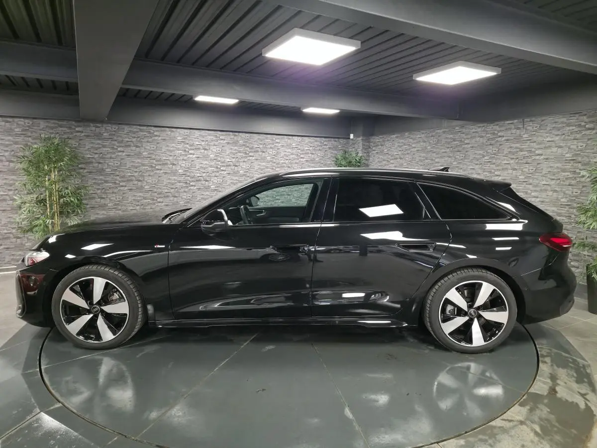 Audi A5 Avant noire vue de profil côté gauche dans un showroom avec jantes 5 branches doubles brillantes.