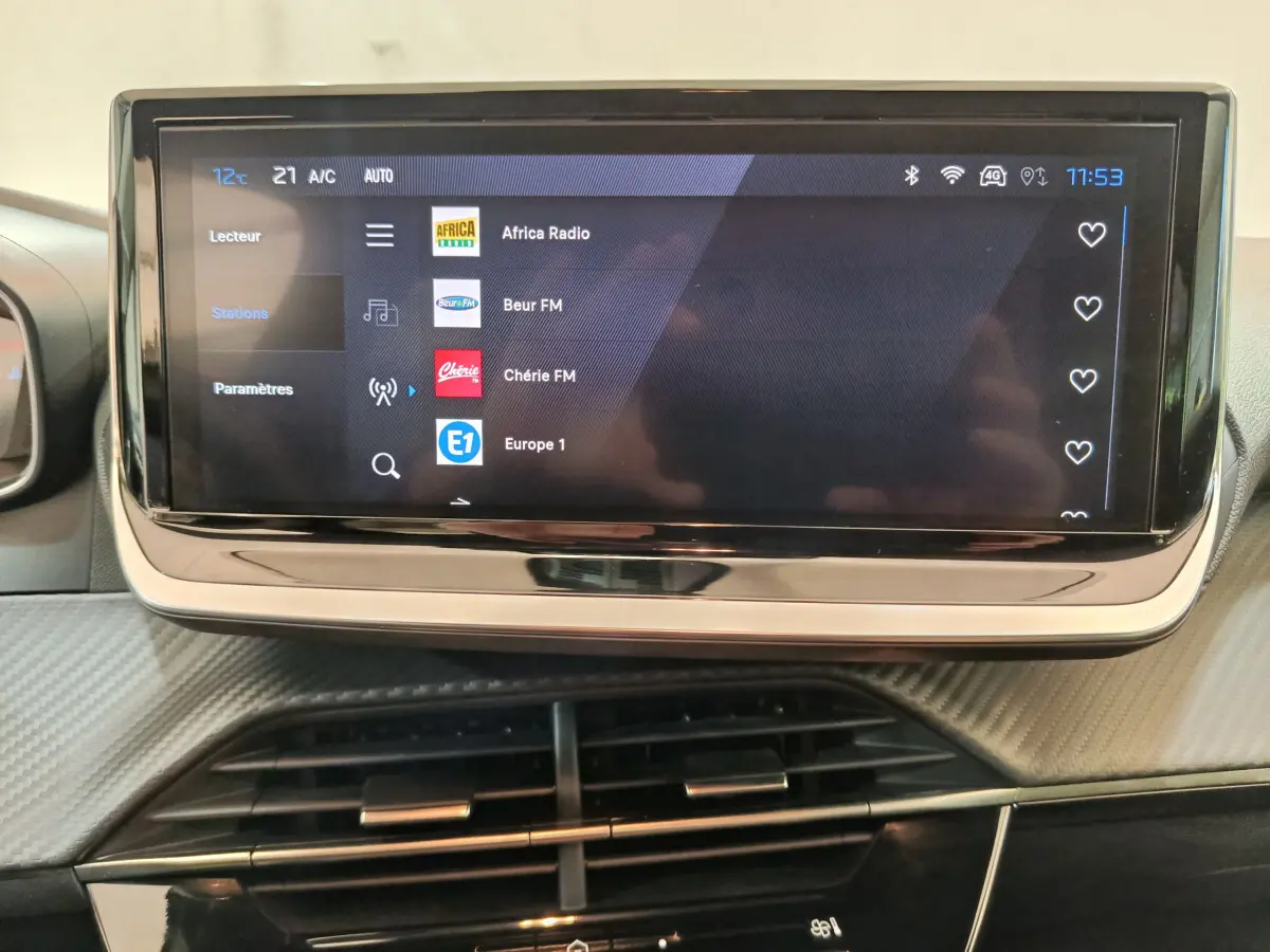 Écran tactile central de 10 pouces affichant les stations radio dans l'habitacle d'une Peugeot 208 gris clair