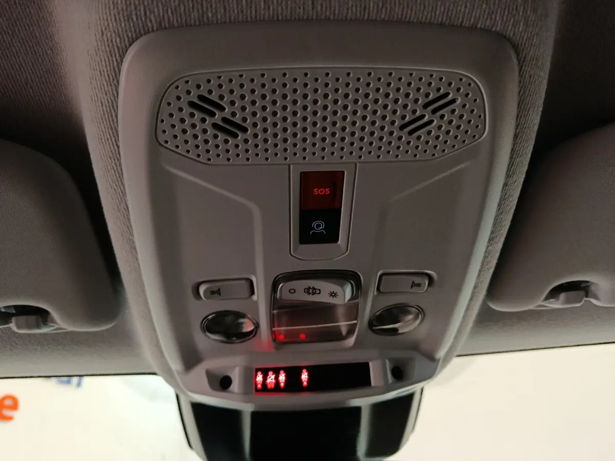 Vue en gros plan du panneau de commandes au plafond intérieur de la Peugeot 208 gris clair, avec bouton SOS rouge allumé.