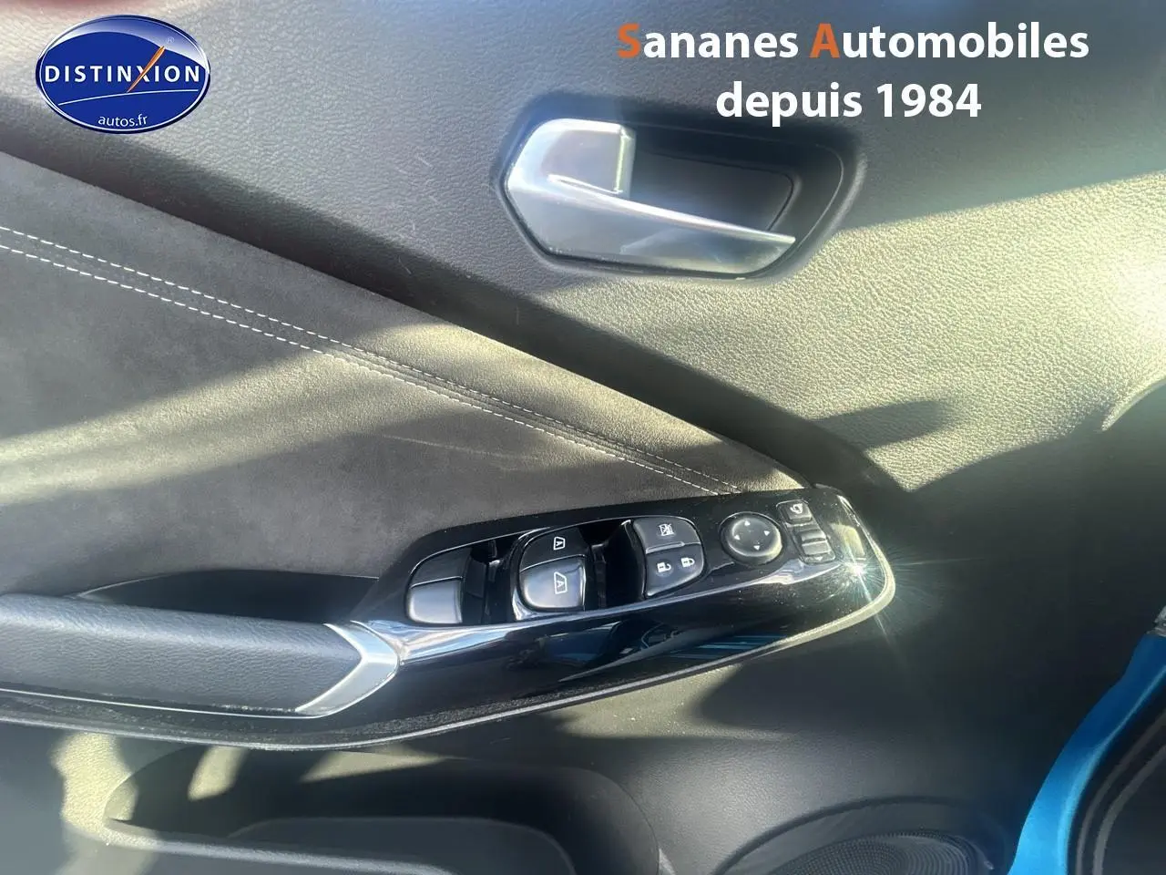 Détail des commandes de lève-vitres et rétroviseurs sur la porte avant gauche d’un Nissan Juke bleu clair 2020.